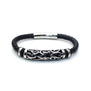 Close-up of braided black leather bracelet with hollow silver floral patterned charm