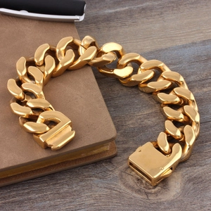 Mens thick gold Cuban chain bracelet in titanium steel displayed on a wooden desk