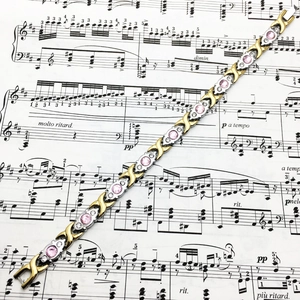 Détail du bracelet magnétique bicolore avec pierres roses sur partition ancienne