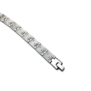 Macro view of titanium steel bracelet featuring Greek key patterns and fold-over clasp