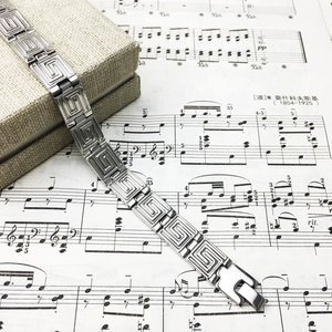 Silver stainless steel bracelet with Greek key pattern links on a gift box background