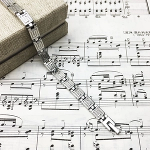 Titanium steel couple bracelet with Greek key pattern on musical score background