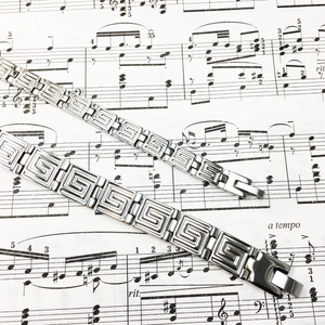 Titanium steel couple bracelet with Greek fret pattern on musical score background