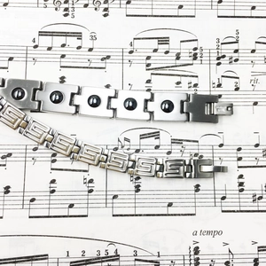 Detail showing two stainless steel bracelets with magnetic black stones and pattern