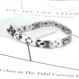 Polished stainless steel magnetic therapy bracelet for men and women on marble background