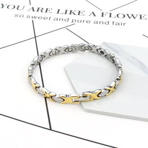 Titanium magnetic bracelet with golden XO link design on marble display stand