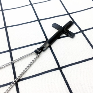 Pendentif croix inversée en acier inoxydable noir avec chaîne argentée sur fond quadrillé