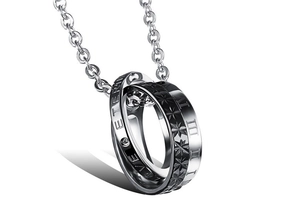 Macro detail of intertwined silver and black rings with Roman numerals and Love engraving