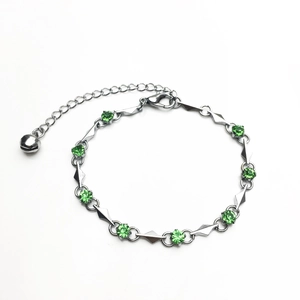 Silver geometric bracelet with faceted green zircons and a small bell pendant charm