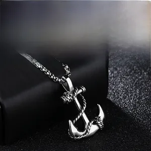 Macro shot of anchor pendant with rope texture and box chain on textured display