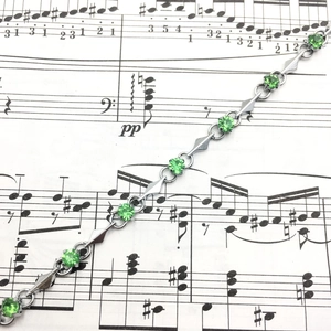 Detailed macro view of green cubic zirconia stones and silver geometric metal links