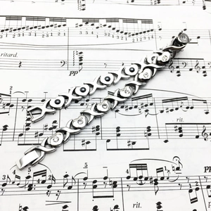 Bracelets XOXO en acier poli avec strass posés sur une partition musicale élégante
