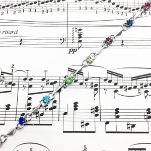 Detailed shot of multicolor zircon bracelet on a sheet music background with silver links