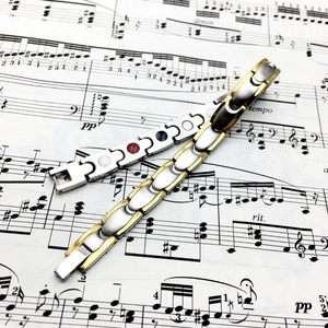 Polished silver and gold-toned magnetic therapy bracelets on a vintage sheet music background
