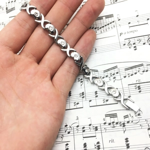 Bracelet XOXO en acier poli avec cœurs et oxydes de zirconium ronds sur partition musicale