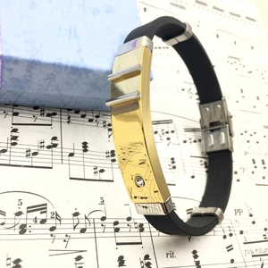 Detail of black silicone bracelet with gold metal plate and inlaid crystal on music sheet