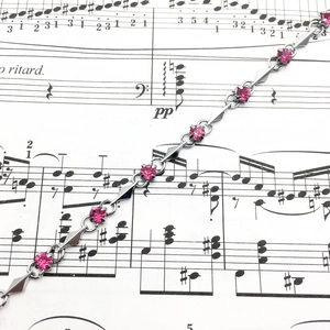 Detailed macro view of silver chain bracelet with pink zircons and geometric links