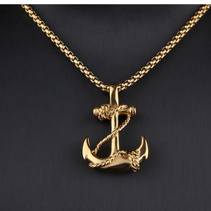 Close-up of golden anchor pendant with rope detail on a metallic box chain necklace