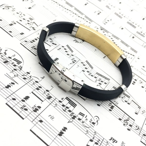 Men's retro stainless steel and black silicone bracelet placed on sheet music background