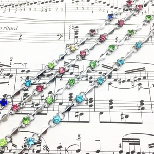Close-up of silver-tone bracelets featuring multi-color cubic zirconia and geometric links