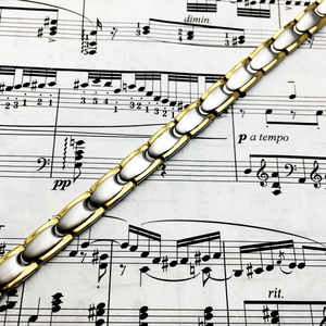 Polished silver and gold titanium steel magnetic therapy bracelet on musical notes
