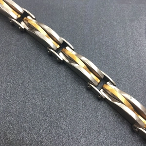 Men's two-tone stainless steel link bracelet with gold accents and geometric texture