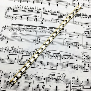 Detailed view of dual-tone titanium steel magnetic therapy bracelet on music sheet background