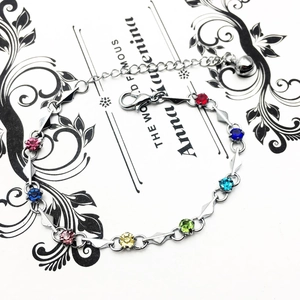 Detail of silver bracelet with colorful crystals, lobster clasp and small bell charm