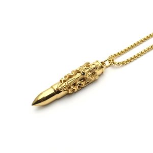 Detailed macro view of golden bullet pendant with cross relief and black gemstone