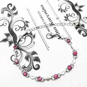 Detailed macro view of silver-tone bracelet with pink crystals and geometric charm links