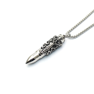 Detail of bullet pendant with intricate hollow carvings on a silver metal chain