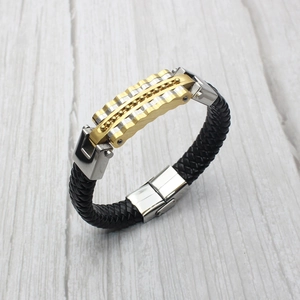 Nahaufnahme des geflochtenen schwarzen Lederarmbands mit gold-silbernem Wellen-Element