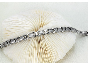 Vue macro du bracelet poli en argent avec maillons en cœur et X sur fond blanc