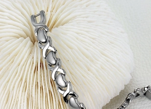 Vue rapprochée d'un bracelet gourmette argenté cœur et X avec des finitions polies