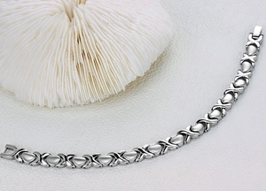 Bracelet pour femme en argent poli avec maillons cœur et X et fermoir pliant sur blanc