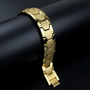 Detail of a bold gold stainless steel bracelet with hexagonal links and a folding clasp