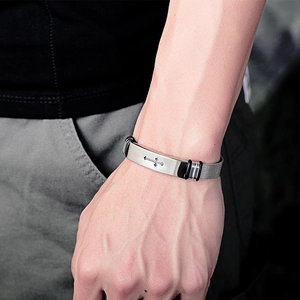Nahaufnahme eines Herren-Mesh-Armbands mit polierter silberner Platte und Kreuz-Emblem