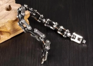 Detail of silver and black stainless steel bicycle chain bracelet on dark wood