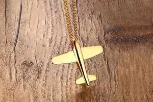 Macro shot of a polished gold airplane pendant on a vintage brown wooden surface