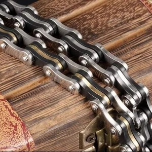 Mens tri-color titanium steel bicycle chain bracelet on vintage wooden background