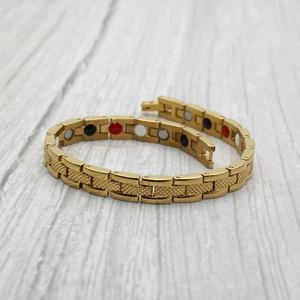Détail du bracelet magnétique doré avec texture à écailles et pierres de soins colorées