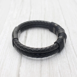 Men's double-layered black braided leather bracelet with magnetic buckle on wood background