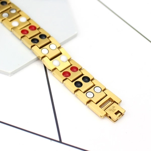 Detailed macro view of gold-tone stainless steel magnetic therapy links with stone inserts