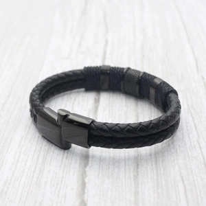 Men's double-strand braided black leather bracelet with magnetic metal clasp and wood background