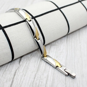 Magnetic steel and gold ion-plated bracelet for women on a checkered fabric and wood background