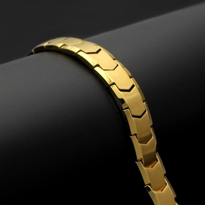 Close-up of gold herringbone fishbone links with brushed finish on black pedestal