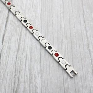 Two-tone wavy titanium steel bracelet with magnetic therapy inserts on wood background