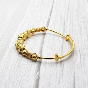 Detail of adjustable gold-plated baby bangle with 12 zodiac charms and textured beads