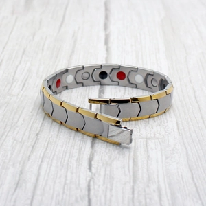 Detail view of bicolor magnetic therapy bracelet with healing stones on wood background