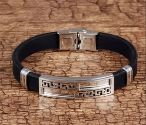 Detail of stainless steel clasp with hollow greek pattern on black silicone bracelet